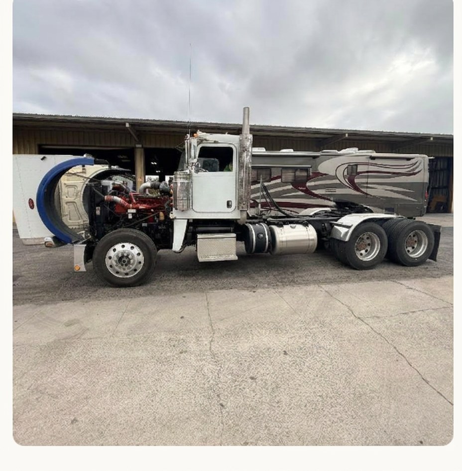 White semi truck with hood open in front of the service bays